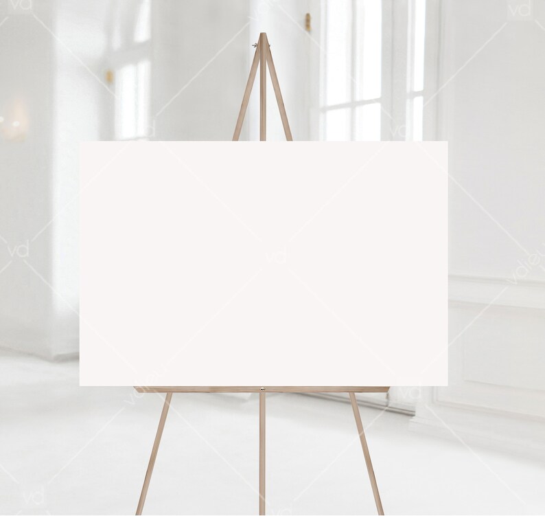 May include: A white canvas on a wooden easel, standing in a white room with a window in the background.