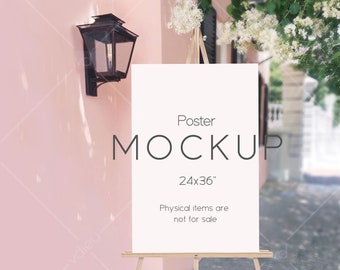 May include: A white poster mockup on an easel with the text "Poster Mockup 24x36" and "Physical items are not for sale". The poster is in front of a pink wall with a black lantern.