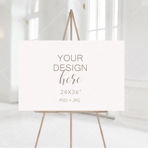 May include: A white sign on an easel with the text "YOUR DESIGN here 24X36" PSD + JPG"