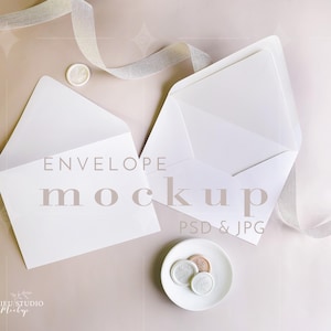 May include: Two white envelopes, one closed and one open, accompanied by a small white dish containing three circular wax seals. A light-colored ribbon curves across the top. The text ENVELOPE mockup PSD & JPG is visible in the center of the image.