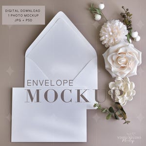 May include: A white envelope mockup featuring an open envelope and a card. The text "ENVELOPE MOCKUP" is displayed on the card. The image also includes decorative white flowers and greenery, set against a neutral background. The top left corner has the text "DIGITAL DOWNLOAD 1 PHOTO MOCKUP JPG + PSD".