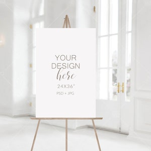 May include: A white canvas sign on an easel with the text "YOUR DESIGN here 24X36" PSD + JPG" in brown text.