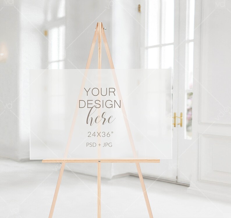 以下が含まれることがあります： 木製のイーゼルに置かれた白いアクリル製の看板。看板には「YOUR DESIGN here 24x36」PSD + JPGと書いてあります。