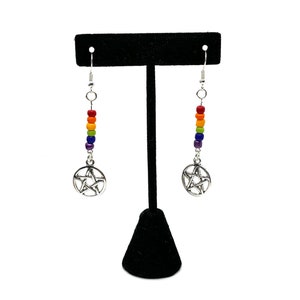 May include: A pair of drop earrings featuring silver-toned pentacle charms suspended from vertical rows of small, multi-coloured beads in red, orange, yellow, green, blue, and purple, attached to silver-toned metal earring hooks.