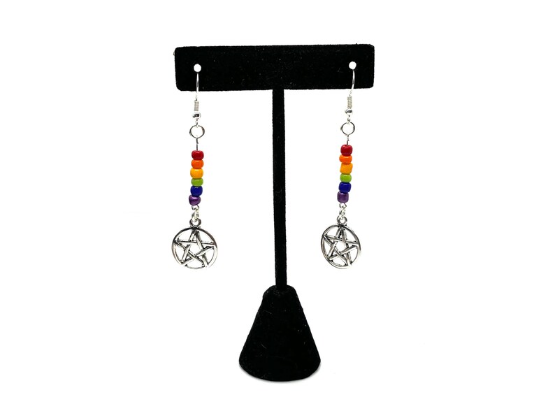 May include: A pair of drop earrings featuring silver-toned pentacle charms suspended from vertical rows of small, multi-coloured beads in red, orange, yellow, green, blue, and purple, attached to silver-toned metal earring hooks.