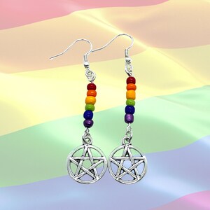 May include: A pair of silver-toned drop earrings featuring a circular pentacle charm suspended from a vertical row of five small, multi-coloured beads in red, orange, yellow, green, blue, and purple, attached to silver-toned earring hooks.