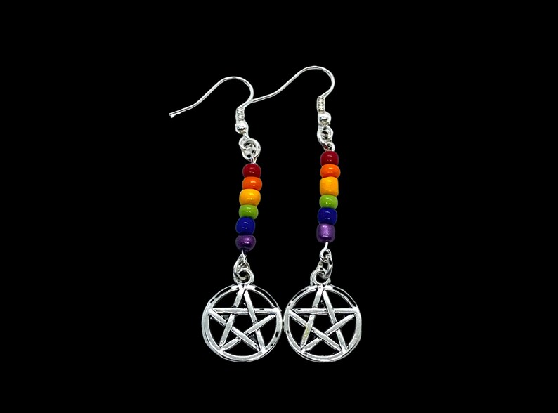 May include: A pair of silver-toned drop earrings featuring a circular pentagram charm suspended from a vertical row of five small, multicoloured beads in red, orange, yellow, green, blue, and purple, attached to silver-toned ear hooks.