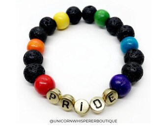 Può includere: Un braccialetto di perline con pietre laviche nere porose alternate a perline lisce e colorate in rosso, arancione, giallo, verde, blu e viola, oltre a perline con lettere dorate che compongono la parola PRIDE. @UNICORNWHISPERERBOUTIQUE