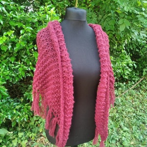 Peut inclure: Un châle en tricot bordeaux avec des franges sur les bords. Le châle est drapé sur un mannequin noir.