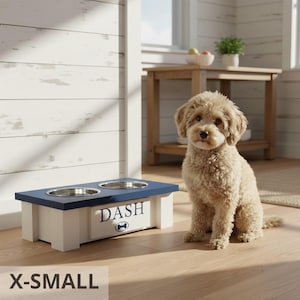 Extra small personalized elevated feeder “DASH” with curly-haired dog beside it. Farmhouse style raised wooden dog bowl stand for small breeds and puppies. Features customizable engraved nameplate, removable bowls, and durable handcrafted design. Perfect for small breeds, improves posture and digestion. Available in multiple colors and sizes, this pet feeder combines functionality with farmhouse home décor style.