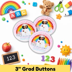 May include: Three 3-inch round graduation buttons with a pink background, rainbow, and a photo of a child in a graduation gown. The buttons are surrounded by colorful school supplies, including a rainbow, blocks, and crayons. The text "Class of 2026" and "Kinder Grad Ashley Brooks" is visible.