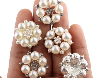 May include: Five pearl and rhinestone embellishments in a variety of styles. The embellishments are round and feature a gold metal base.