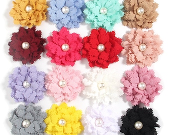 May include: Assortment of 16 fabric flower embellishments with pearl centres. The flowers are in various colours, including red, blue, yellow, pink, white, and black.