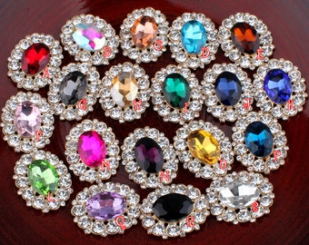 May include: Assortment of 18 oval-shaped rhinestone embellishments in various colours, including red, pink, green, blue, purple, and gold. Each embellishment is surrounded by a circle of smaller rhinestones.
