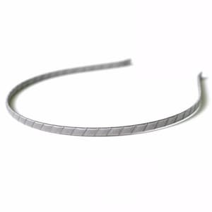 May include: A silver headband with a textured, patterned design.