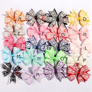 May include: Twenty-one hair bows with a variety of colors and lace patterns. The bows are arranged in rows and labeled with letters A through T.