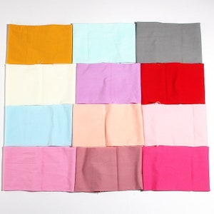 Puede incluir: Doce muestras de tela en varios colores, incluyendo amarillo, azul claro, gris, blanco, morado, rojo, rosa, melocotón, marrón y rosa intenso.