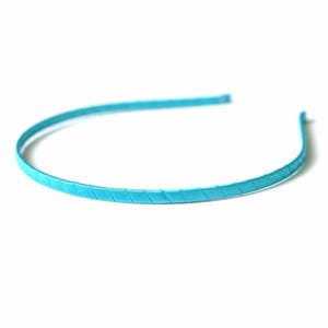 May include: A turquoise blue headband with a textured design.