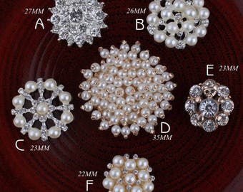 May include: Assortment of six pearl and rhinestone embellishments in various sizes and styles. The embellishments are arranged on a wooden surface. The embellishments are labeled with letters A through F and their corresponding measurements in millimeters.