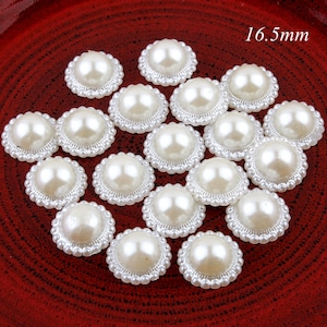 May include: A collection of 16.5 mm white pearl embellishments with a beaded edge. The pearls are arranged on a red surface.