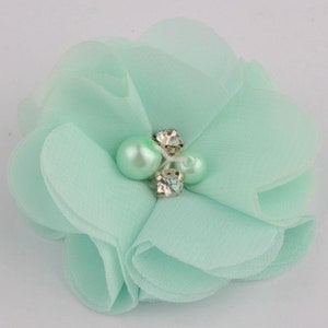 May include: A light green fabric flower with a pearl and rhinestone embellishment.
