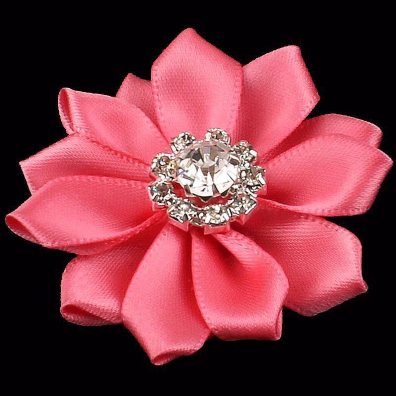 May include: A pink satin flower with a silver rhinestone center.