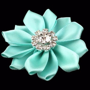 May include: A turquoise satin flower with a rhinestone center.