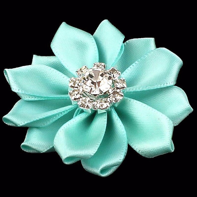 May include: A turquoise satin flower with a rhinestone center.
