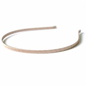May include: A thin, beige metal headband with a textured, striped design.