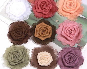 Puede incluir: Nueve adornos de rosas de tela en varios colores, incluyendo blanco, rojo, melocotón, marrón, rosa, verde, beige y morado. Cada rosa tiene un diseño de pétalos en capas y un borde con volantes, para manualidades.