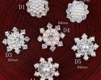 May include: Assortment of six pearl and rhinestone embellishments in gold settings.  The embellishments are in two shapes: round and snowflake.  The round embellishments are 20 mm in diameter and the snowflake embellishments are 22 mm in diameter.  The embellishments are labeled D1, D2, D3, D4, D5, and A1.