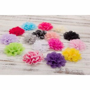 May include: Assortment of 14 small fabric flower embellishments in various colors, including pink, purple, yellow, green, white, and black. The flowers are made of a soft, layered fabric and have a delicate lace trim.