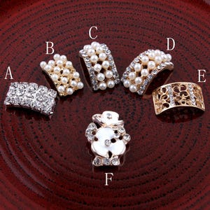 May include: Assortment of six decorative embellishments for crafts and jewelry making. The embellishments include a snowman design, a flower design, and four different styles of pearl and rhinestone trim.