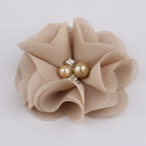 May include: A beige fabric flower with a pearl and rhinestone embellishment.