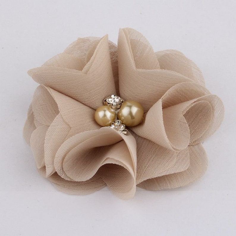 May include: A beige fabric flower with a pearl and rhinestone embellishment.