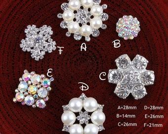 May include: Assortment of six silver-toned embellishments with various designs, including pearl and rhinestone accents. The embellishments are arranged on a red surface. A=28mm, B=14mm, C=26mm, D=28mm, E=26mm, F=21mm.