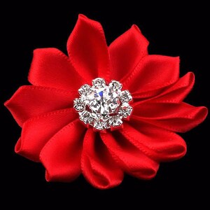 May include: A red satin flower with a silver rhinestone center. The flower is about 3 inches in diameter.