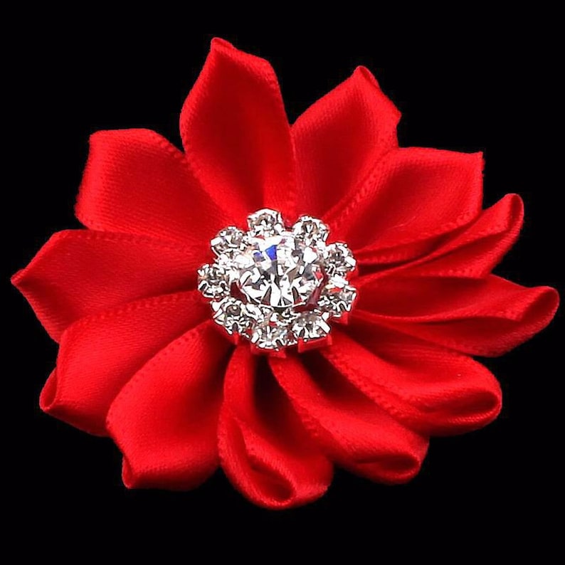 May include: A red satin flower with a silver rhinestone center. The flower is about 3 inches in diameter.