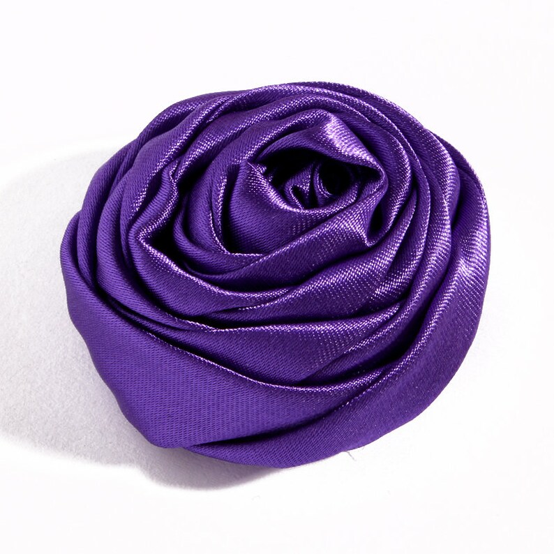 May include: A large, purple satin rose flower. The rose is made of fabric and has a soft, velvety texture.