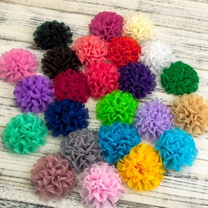 May include: Assortment of 20 colourful fabric flower hair clips. The flowers are made of soft, ruffled fabric and come in a variety of colours, including pink, blue, green, yellow, red, and purple.