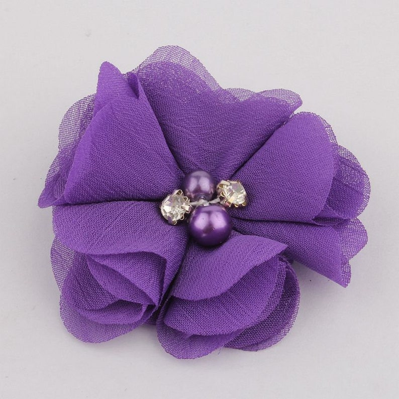 May include: Purple fabric flower with three pearl and rhinestone embellishments.