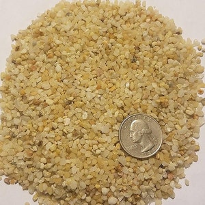 May include: A close-up of a pile of small, light brown and white quartz crystals. A US quarter is included for scale.