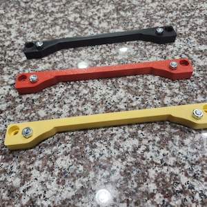 May include: Three plastic strips with different colored finishes: black, red, and yellow. Each strip has two silver screws on either end.