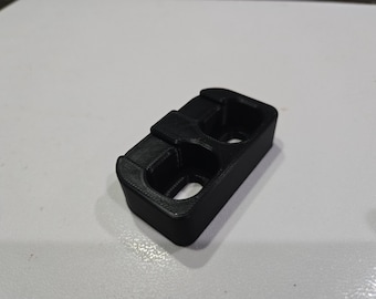 Puede incluir: Un soporte de plástico negro impreso en 3D con dos ranuras para objetos pequeños.