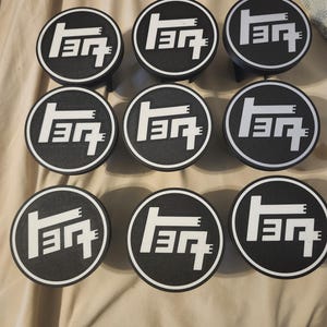 May include: Nine black and white circular car emblems with the Toyota logo. The logo is white and features the brand name in a stylized font. The emblems are arranged in a grid pattern.