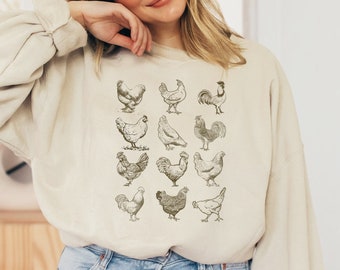 May include: A beige sweatshirt with a graphic print of various chickens and roosters in black and white.