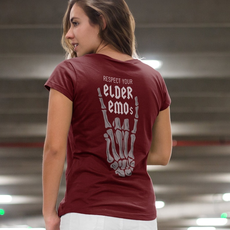 K&ouml;nnte beinhalten: Ein maroonfarbenes T-Shirt mit einer Skeletthand, die das Rock'n'Roll-Zeichen macht. Der Text auf dem Shirt lautet "Respect Your Elder Emos".