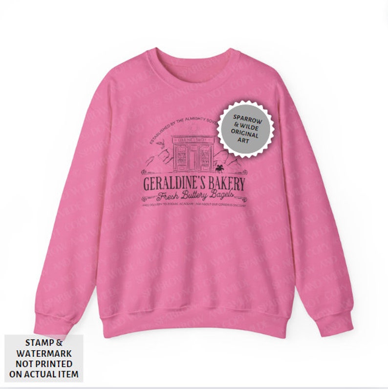 Puede incluir: Sudadera rosa con un dise&ntilde;o gr&aacute;fico negro de una panader&iacute;a llamada "Geraldine's Bakery" con el texto "Fresh Buttery Bagels". El gr&aacute;fico tambi&eacute;n incluye el texto "Established by the Almighty Sovereign" y "A Mile-try to Zoning Academy. How About Our Generous Discount?"