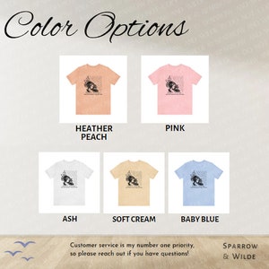 Puede incluir: Se muestran cinco opciones de color de camiseta: melocot&oacute;n brezo, rosa, ceniza, crema suave y azul beb&eacute;. Cada camiseta presenta un gr&aacute;fico en blanco y negro de la cara de una mujer con texto. El texto dice: "Y la respuesta, amigo m&iacute;o, est&aacute; en el viento."