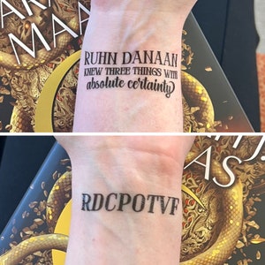 May include: A person's wrist with two tattoos. The top tattoo reads "Ruhn Danaan knew three things with absolute certainty". The bottom tattoo reads "RDCPOTVF".